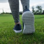 partial view of woman running on green lawn